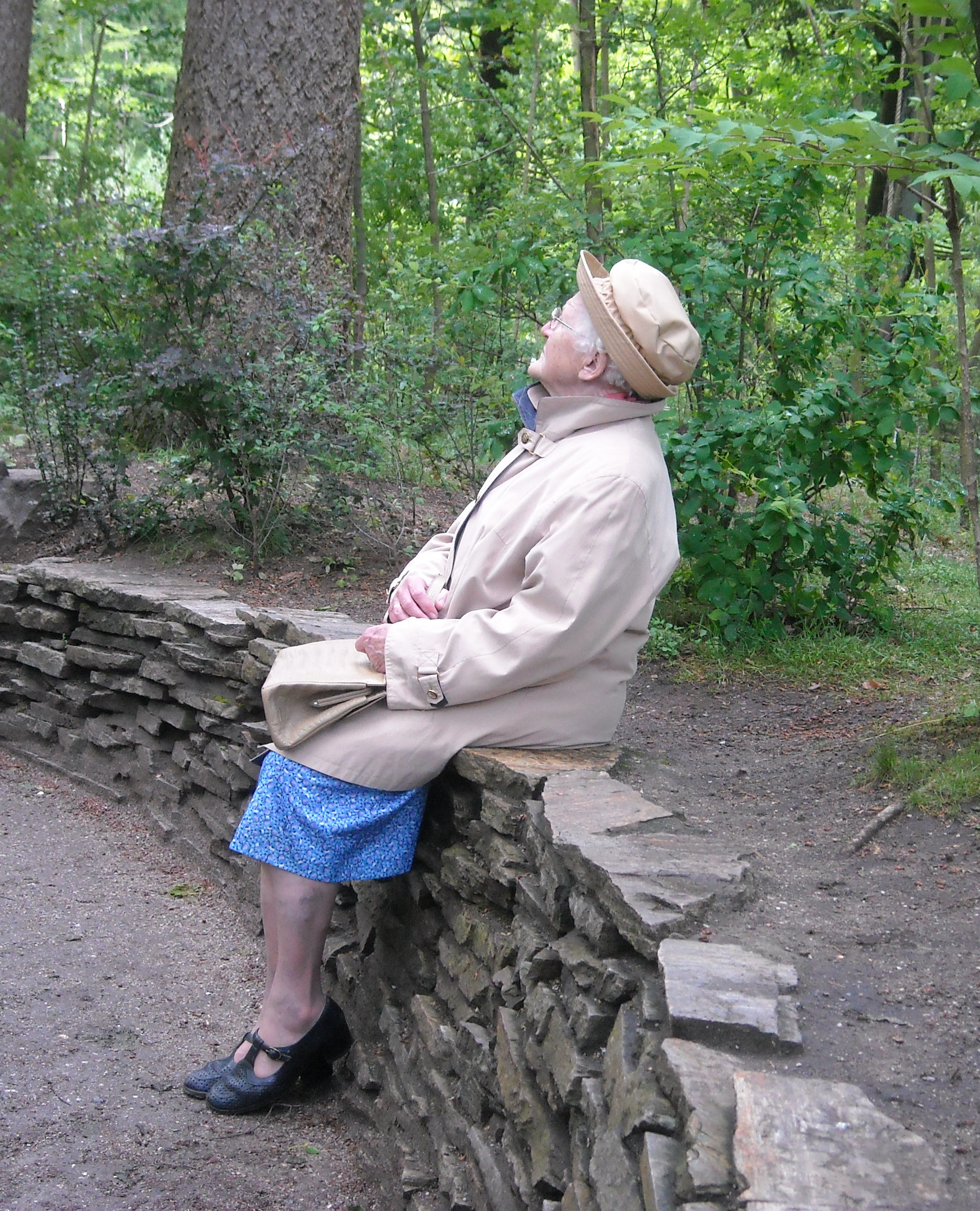 oudere mevrouw zit op een muurtje